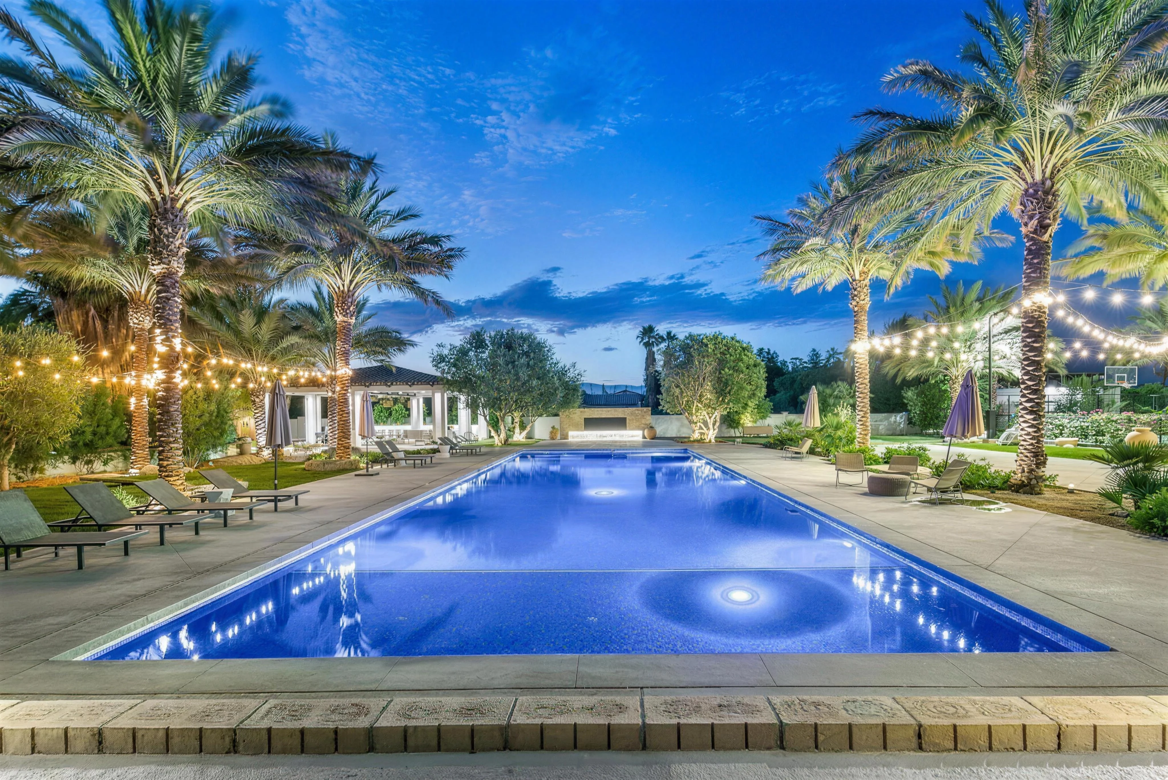 The estate pool lit at dusk beneath string lights